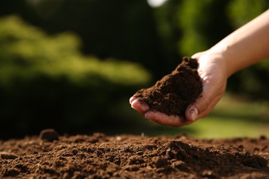 Woman holding pile of soil outdoors, closeup. Space for text