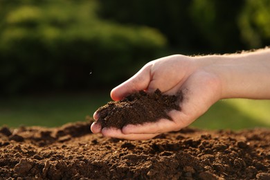 Man holding pile of soil outdoors, closeup. Space for text