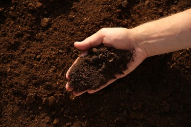 Photo of Man holding pile of soil outdoors, top view. Space for text