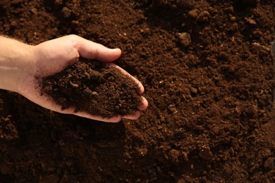 Photo of Man holding pile of soil outdoors, top view. Space for text