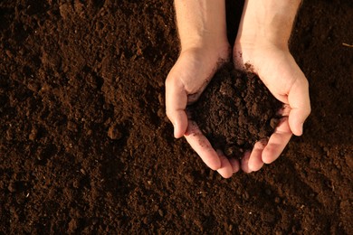 Man holding pile of soil outdoors, top view. Space for text