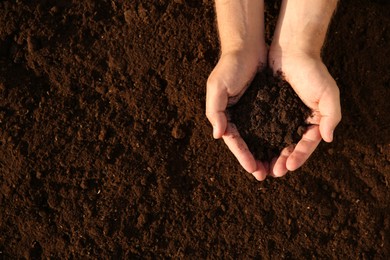 Photo of Man holding pile of soil outdoors, top view. Space for text