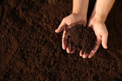 Photo of Man holding pile of soil outdoors, top view. Space for text