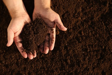 Photo of Man holding pile of soil outdoors, top view. Space for text