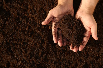 Man holding pile of soil outdoors, top view. Space for text