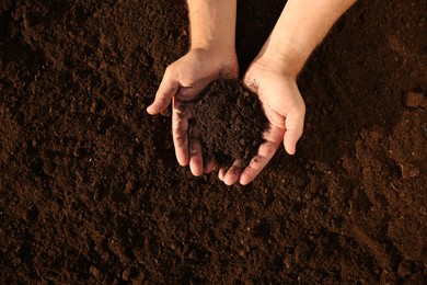 Photo of Man holding pile of soil outdoors, top view. Space for text