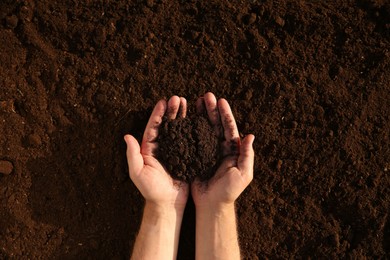 Photo of Man holding pile of soil outdoors, top view