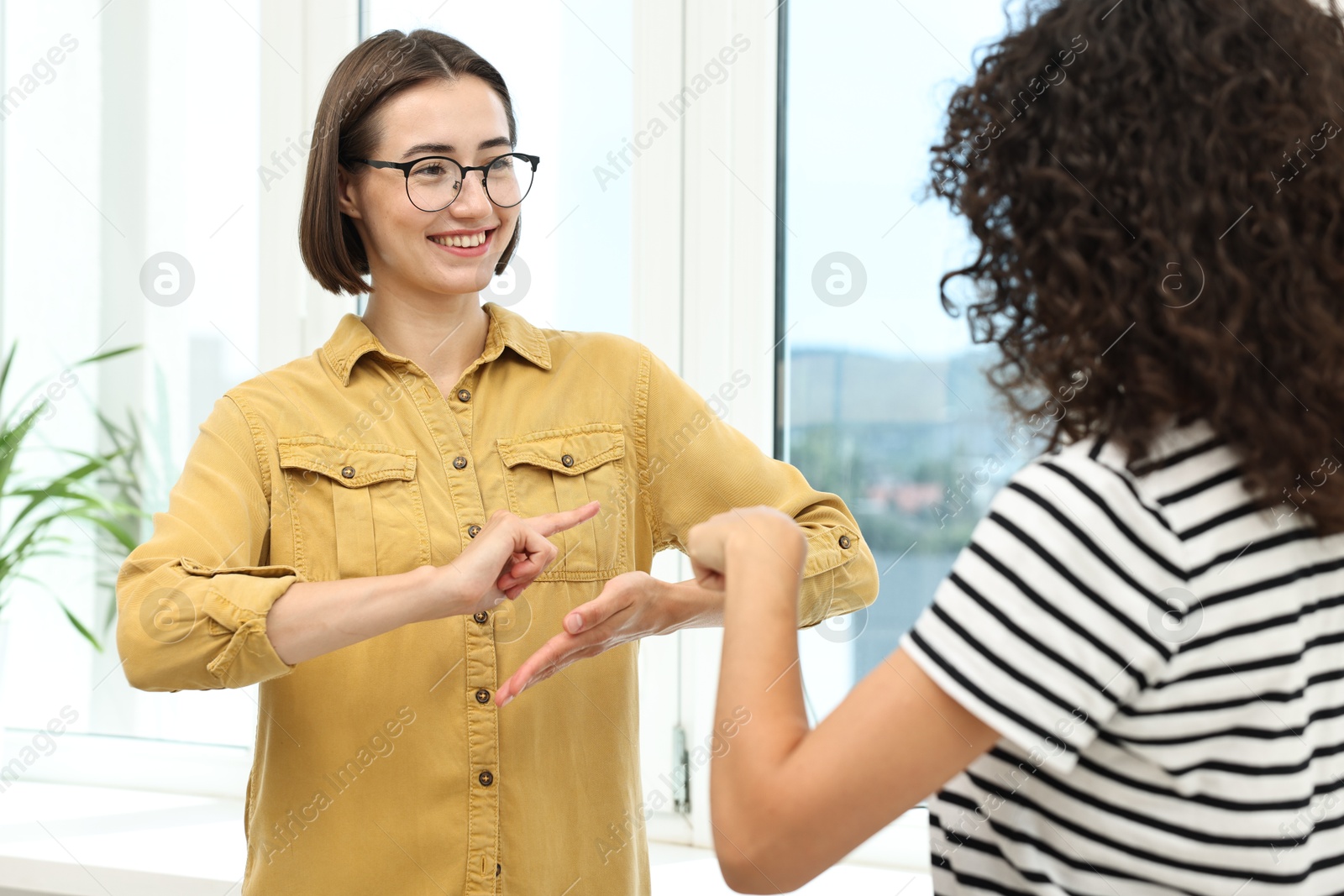 Photo of Young women using sign language for communication indoors