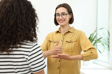 Photo of Young women using sign language for communication indoors
