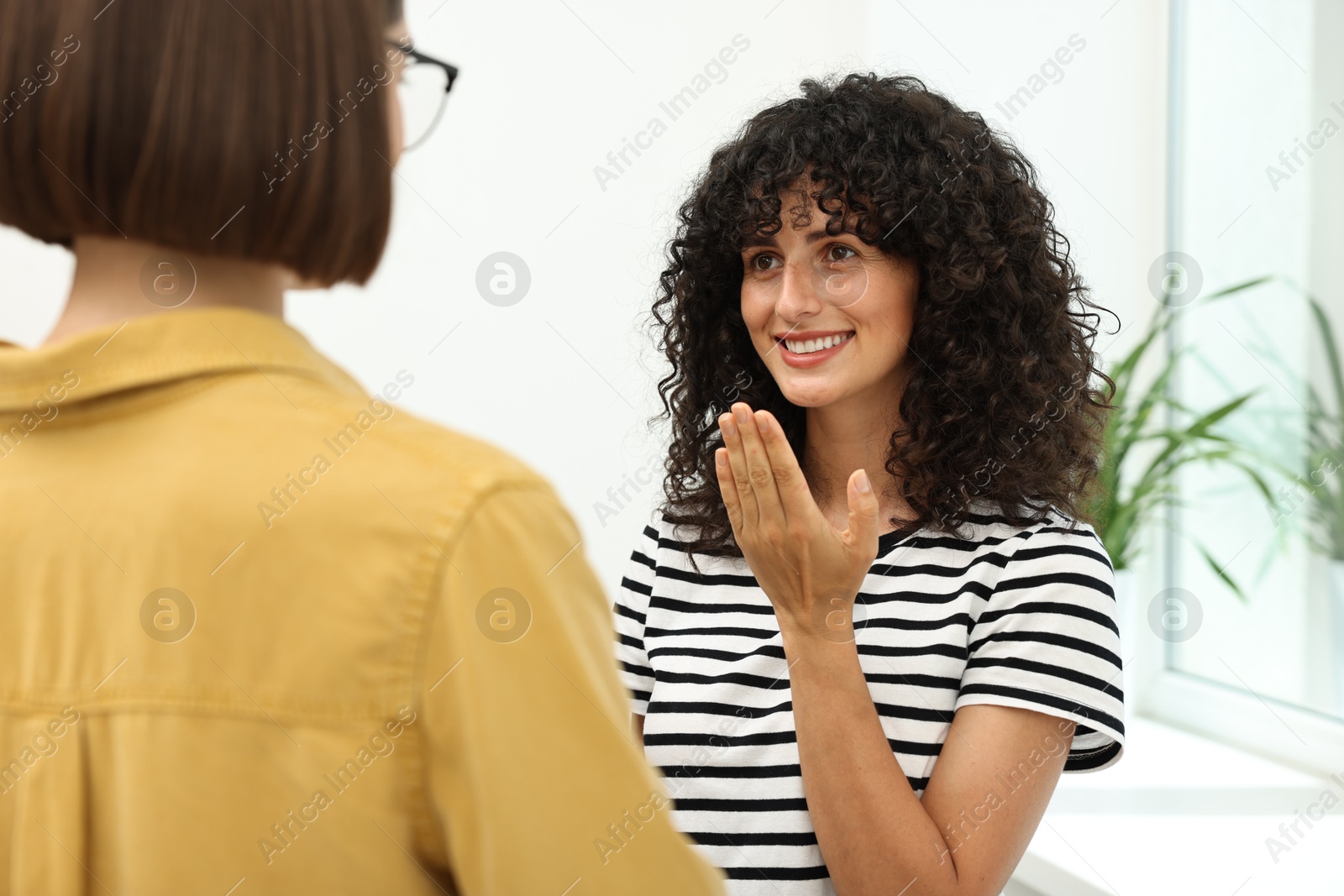 Photo of Young women using sign language for communication indoors