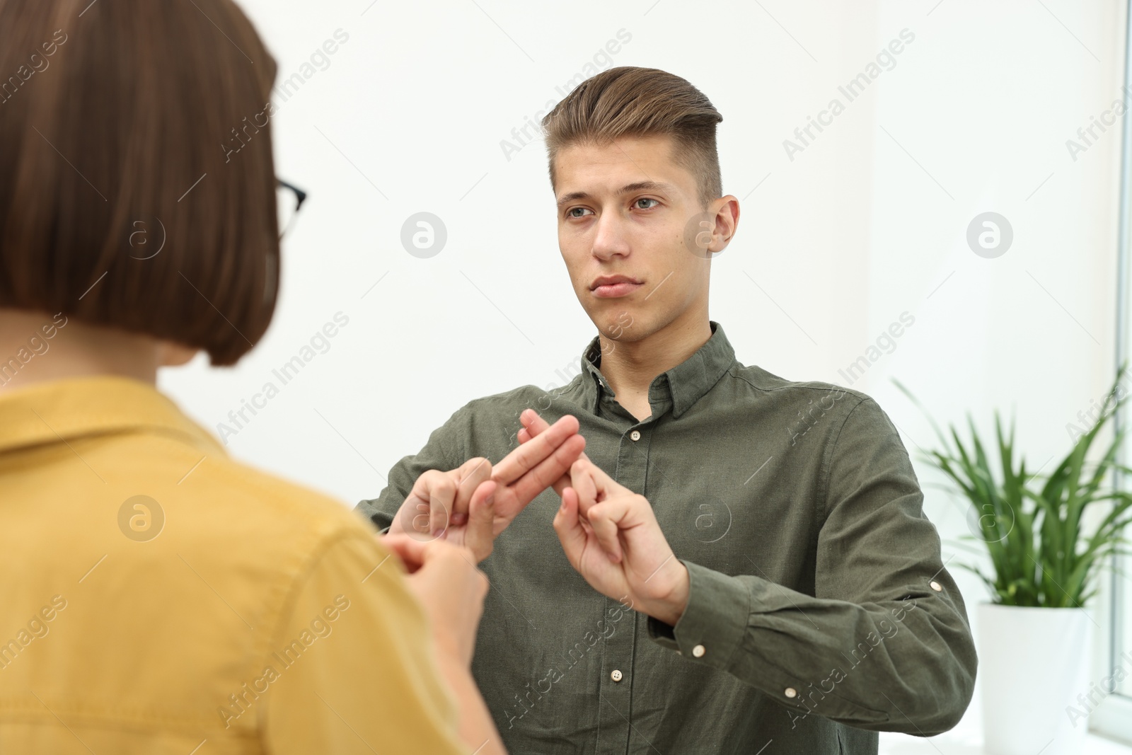 Photo of Man and woman using sign language for communication indoors