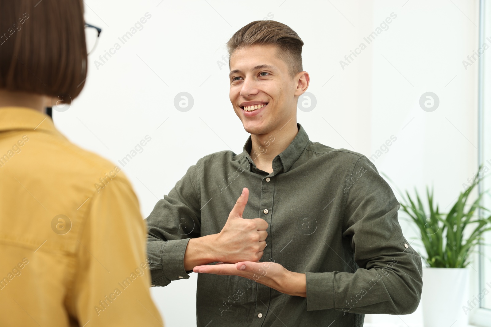 Photo of Man and woman using sign language for communication indoors