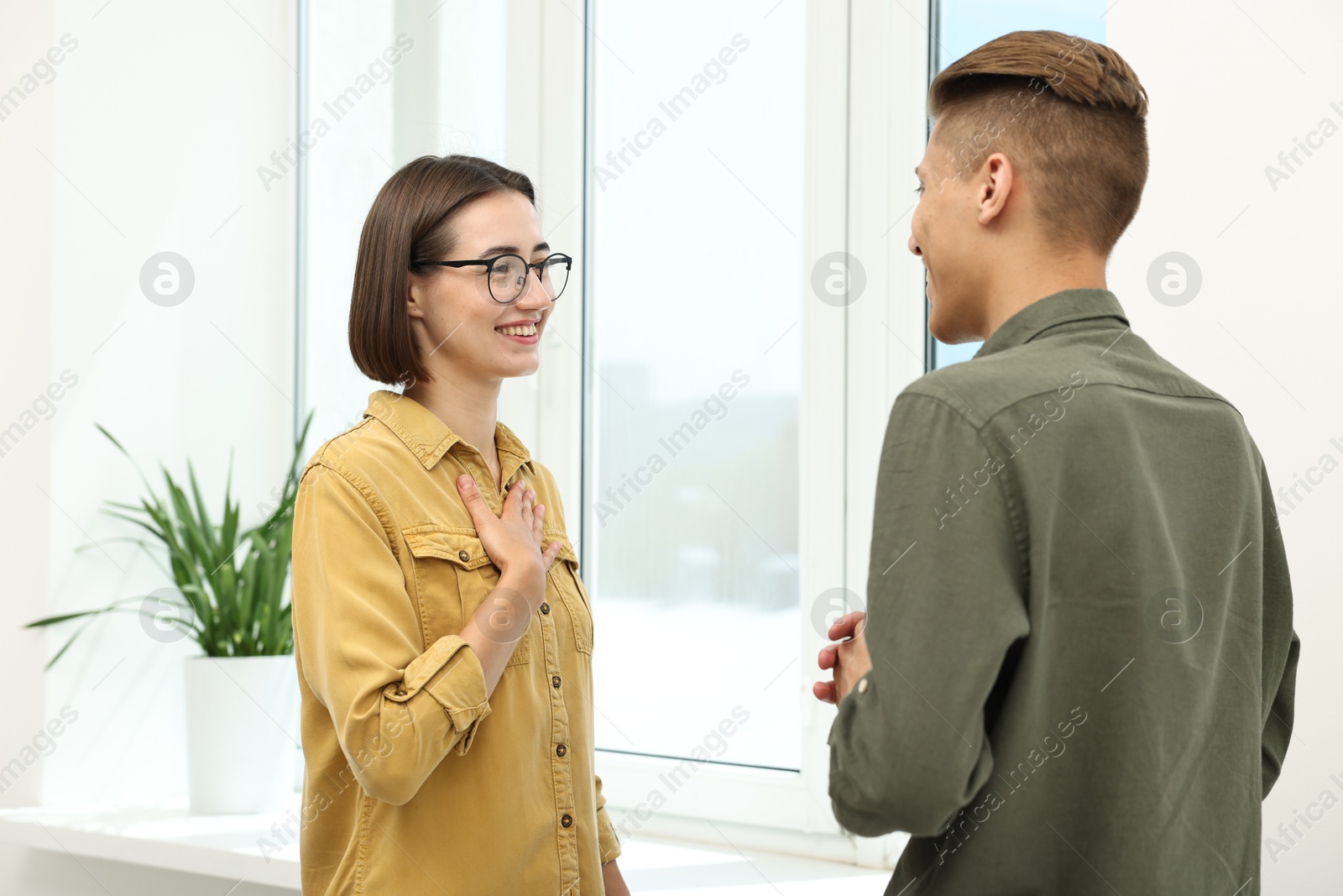 Photo of Man and woman using sign language for communication indoors