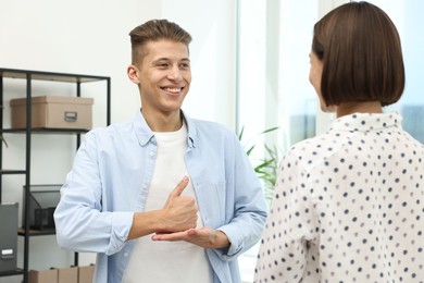 Photo of Man and woman using sign language for communication indoors