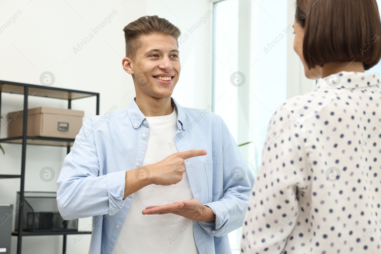 Photo of Man and woman using sign language for communication indoors