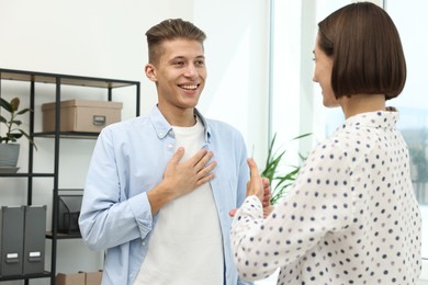 Photo of Man and woman using sign language for communication indoors