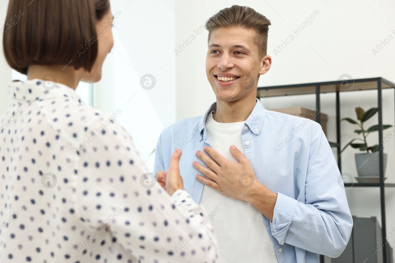 Photo of Man and woman using sign language for communication indoors