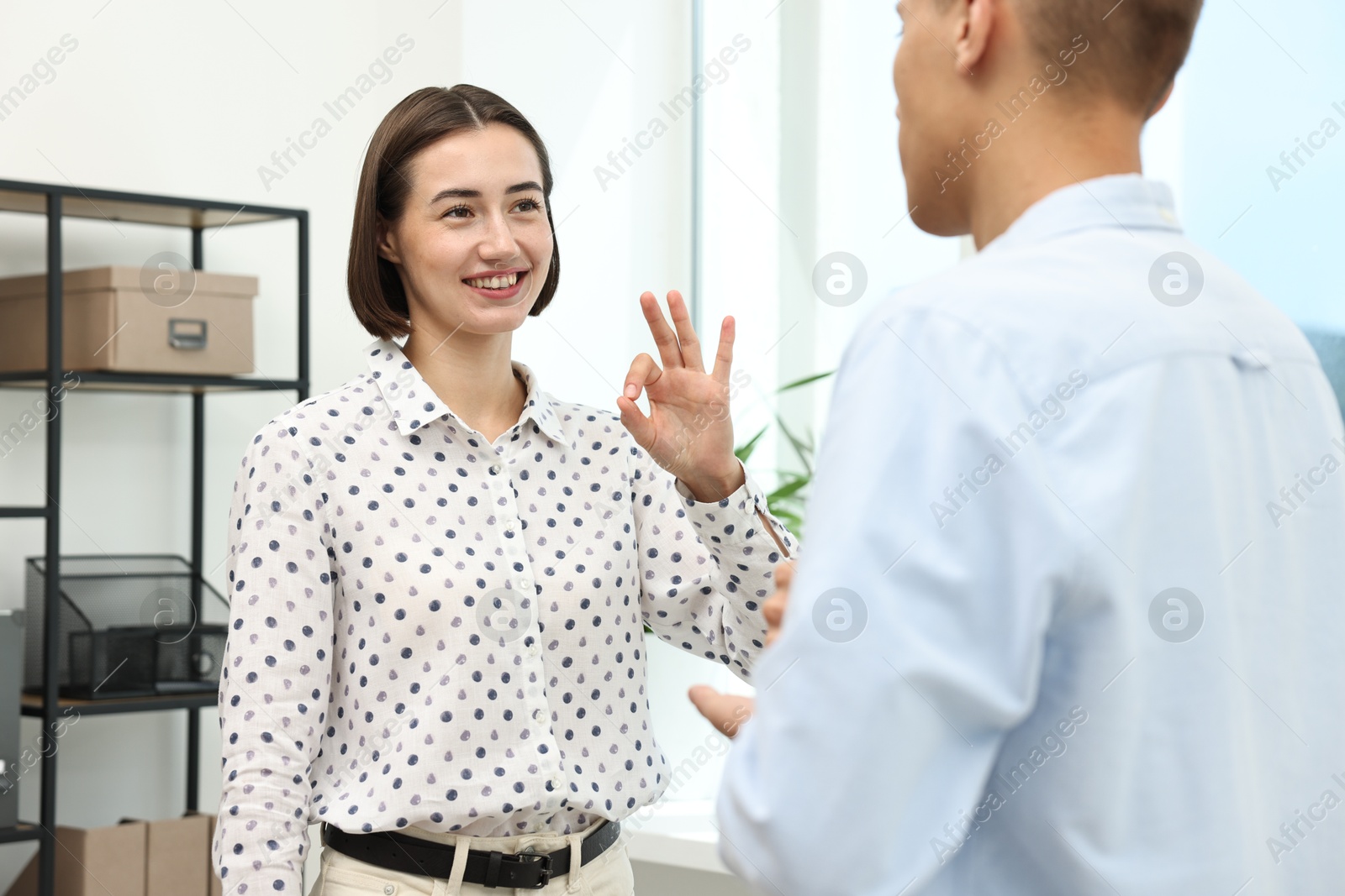 Photo of Man and woman using sign language for communication indoors