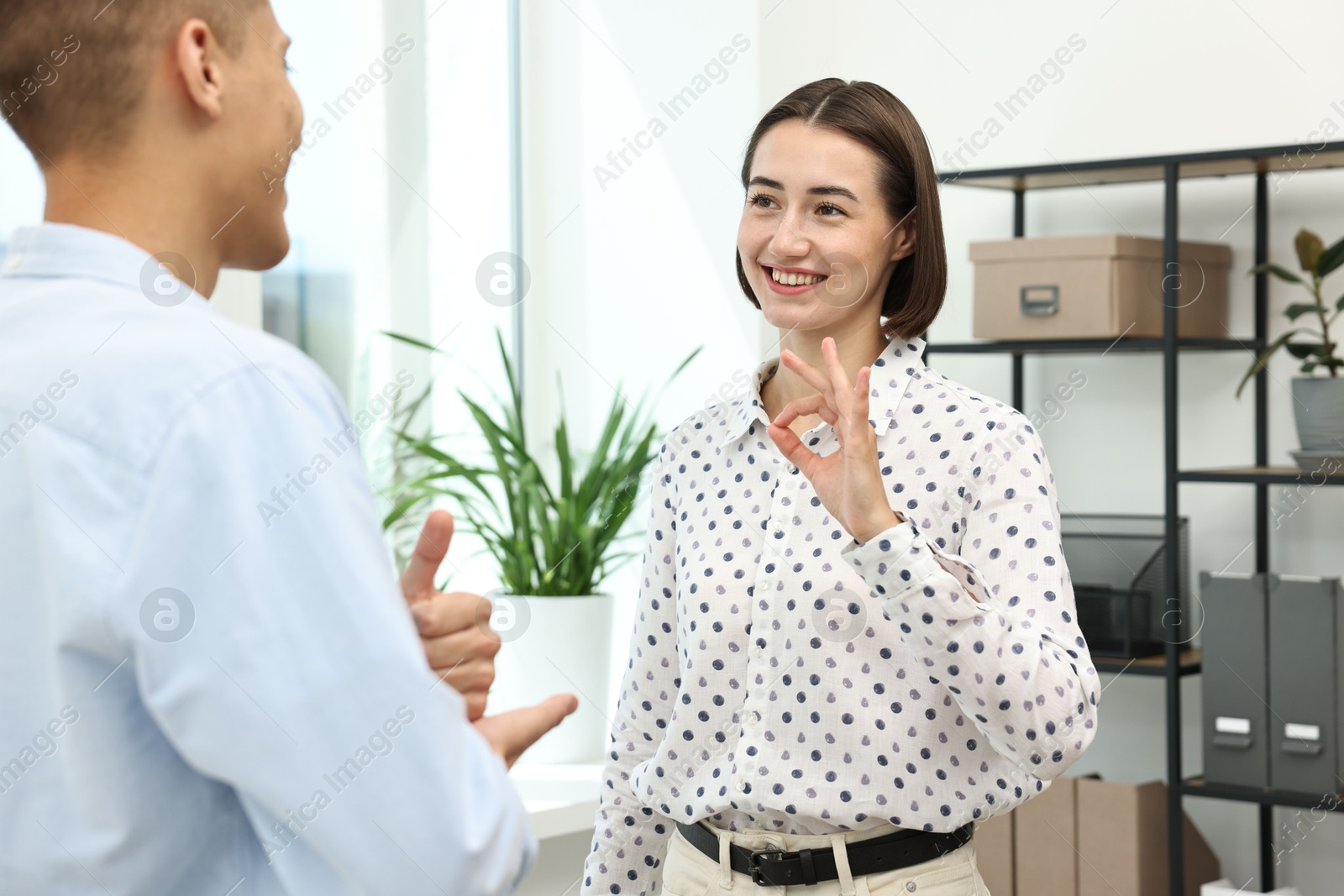 Photo of Man and woman using sign language for communication indoors