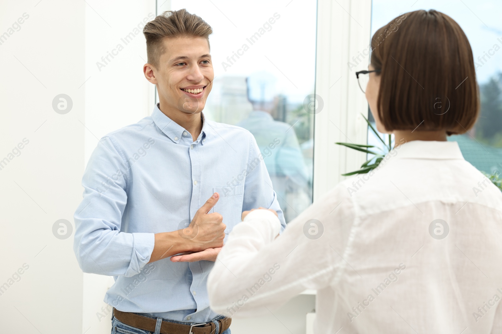 Photo of Man and woman using sign language for communication indoors