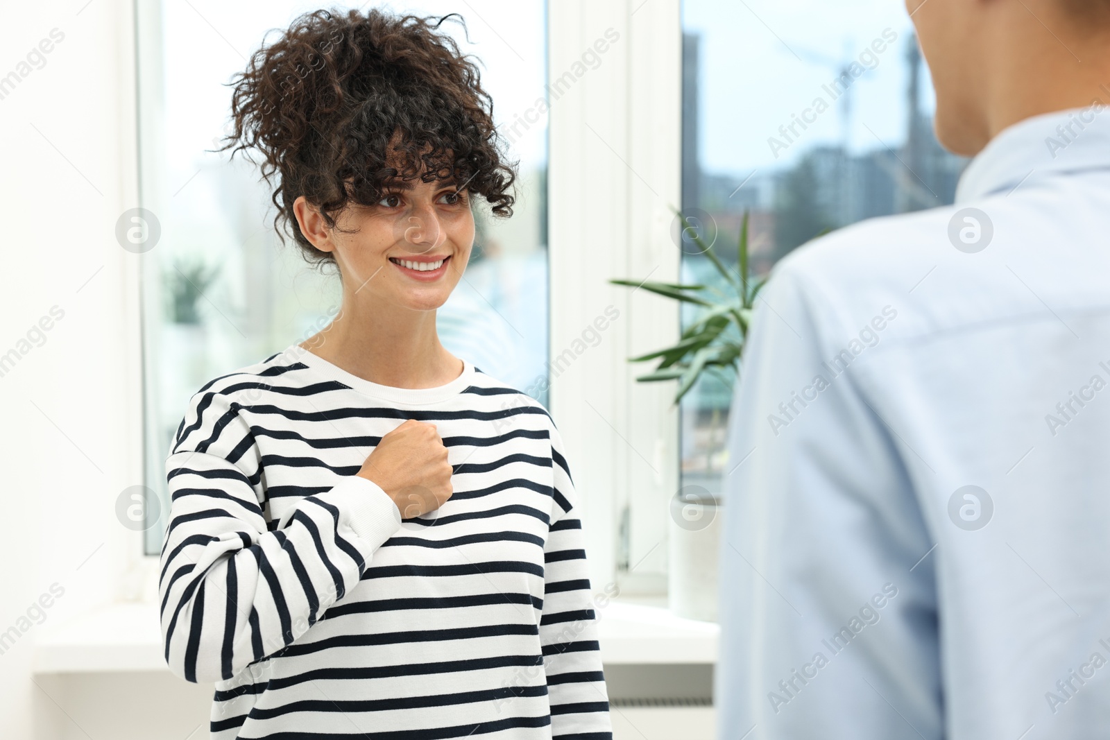 Photo of Man and woman using sign language for communication indoors