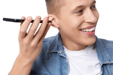 Young man with smartphone listening to voice message on white background