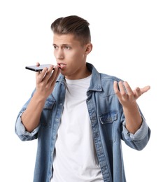 Young man recording voice message via smartphone on white background