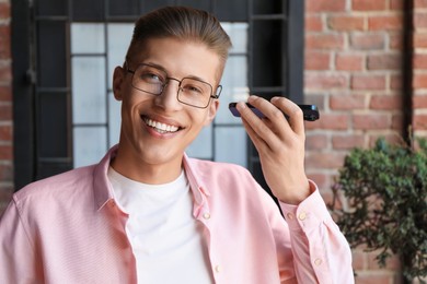 Photo of Young man with smartphone listening to voice message outdoors