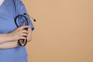 Photo of Professional nurse with stethoscope on dark beige background, closeup. Space for text