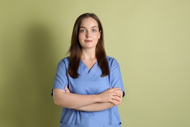 Photo of Professional nurse in uniform on pale green background