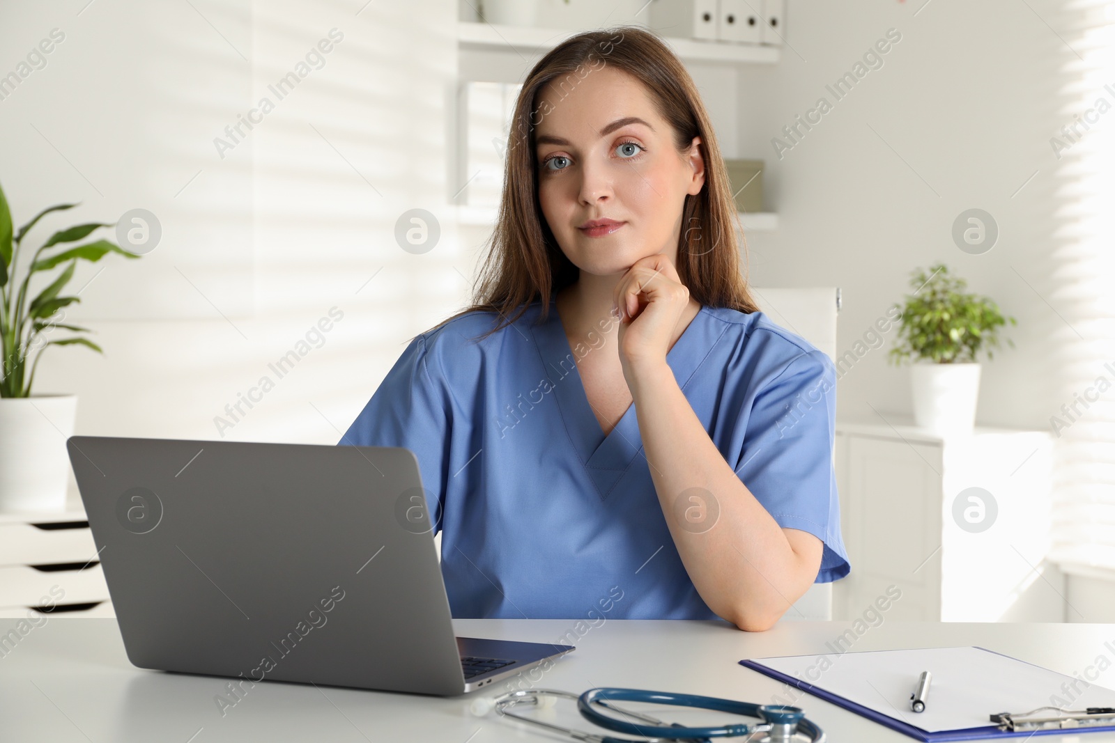 Photo of Young nurse working with laptop at desk in hospital