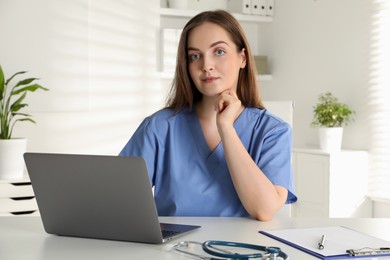 Photo of Young nurse working with laptop at desk in hospital