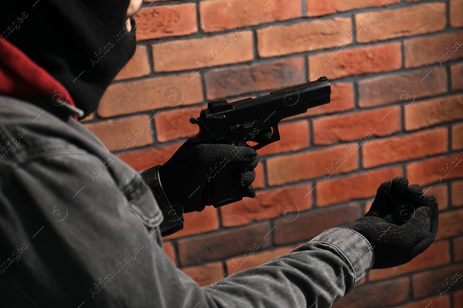 Photo of Dangerous criminal with gun near brick wall, closeup. Armed robbery