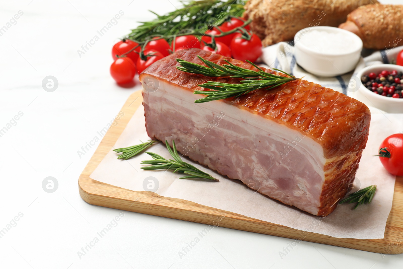 Photo of Piece of raw bacon, rosemary and tomatoes on white marble table