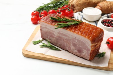 Photo of Piece of raw bacon, rosemary and tomatoes on white marble table