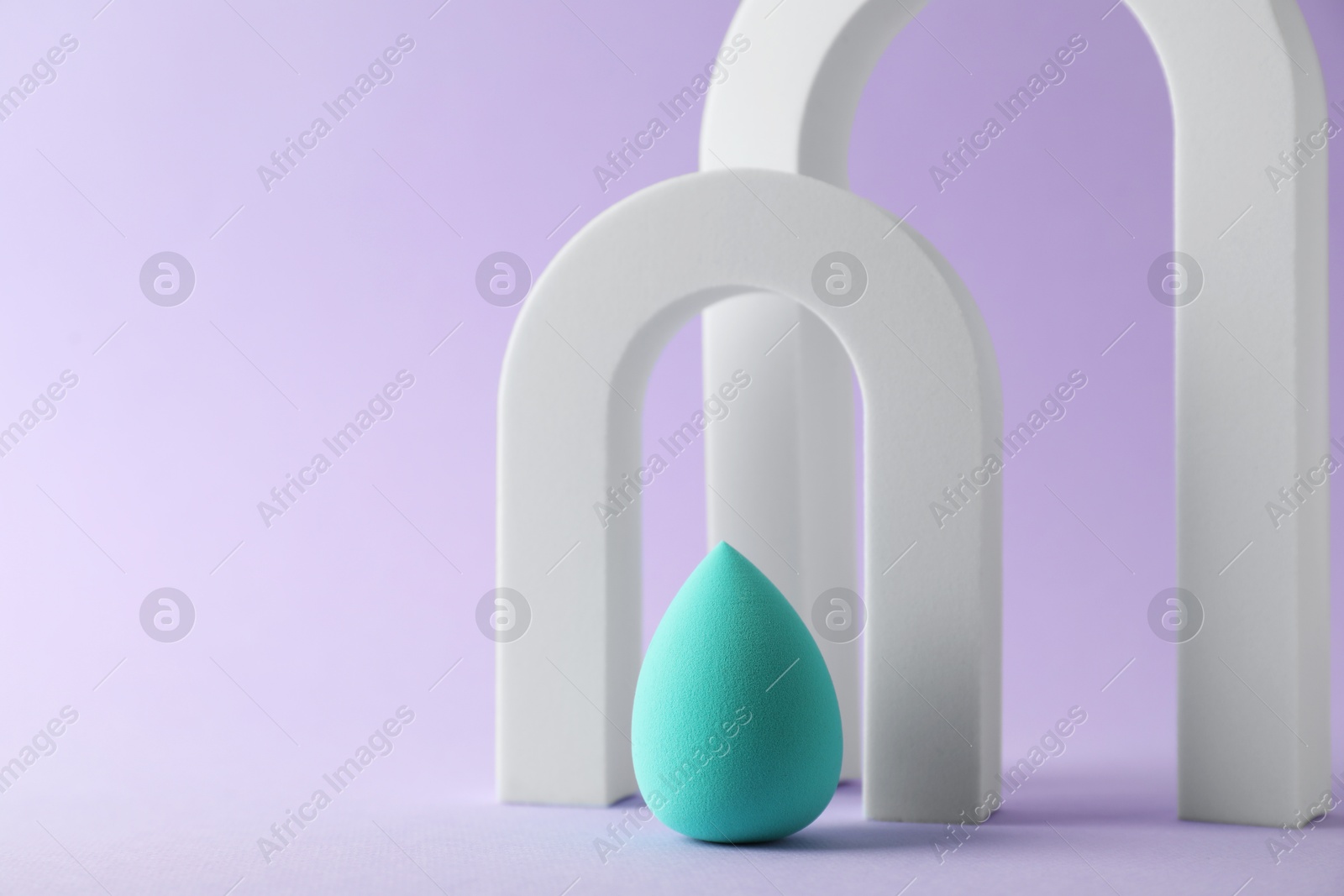 Photo of Stylish presentation of makeup sponge on violet background, space for text