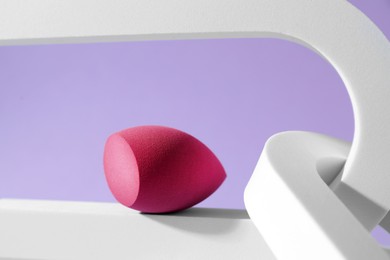 Photo of Stylish presentation of makeup sponge on violet background