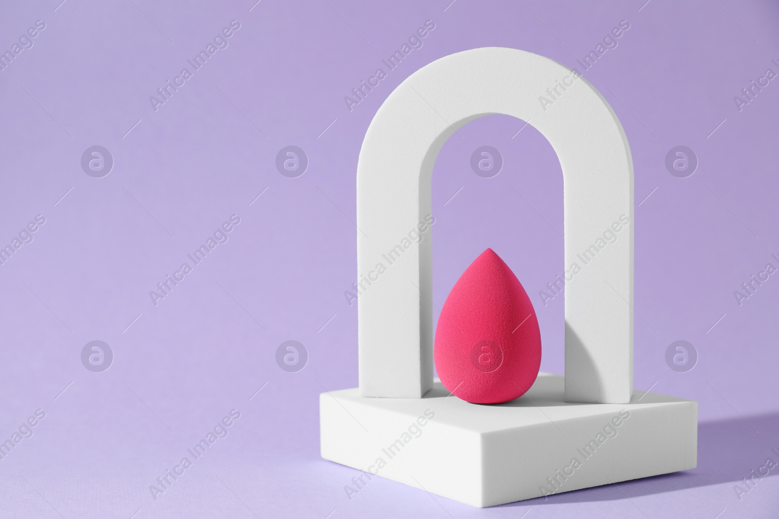 Photo of Stylish presentation of makeup sponge on violet background, space for text