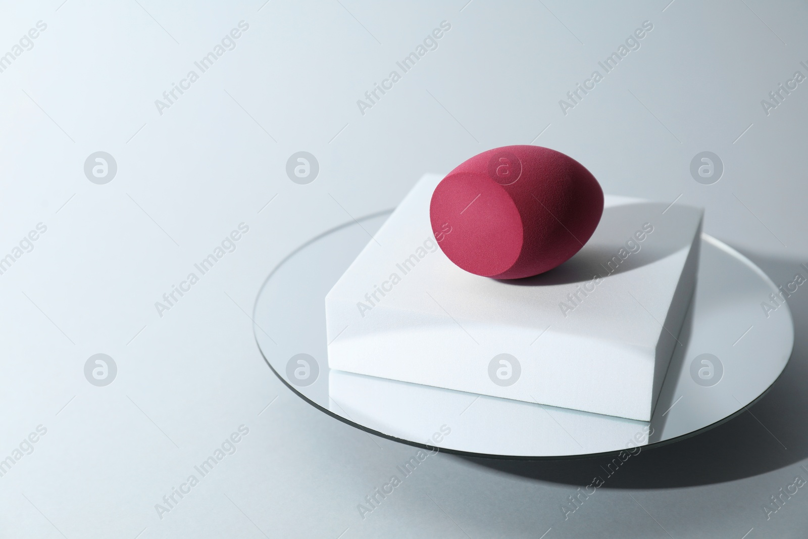 Photo of Stylish presentation of makeup sponge on light grey background, space for text