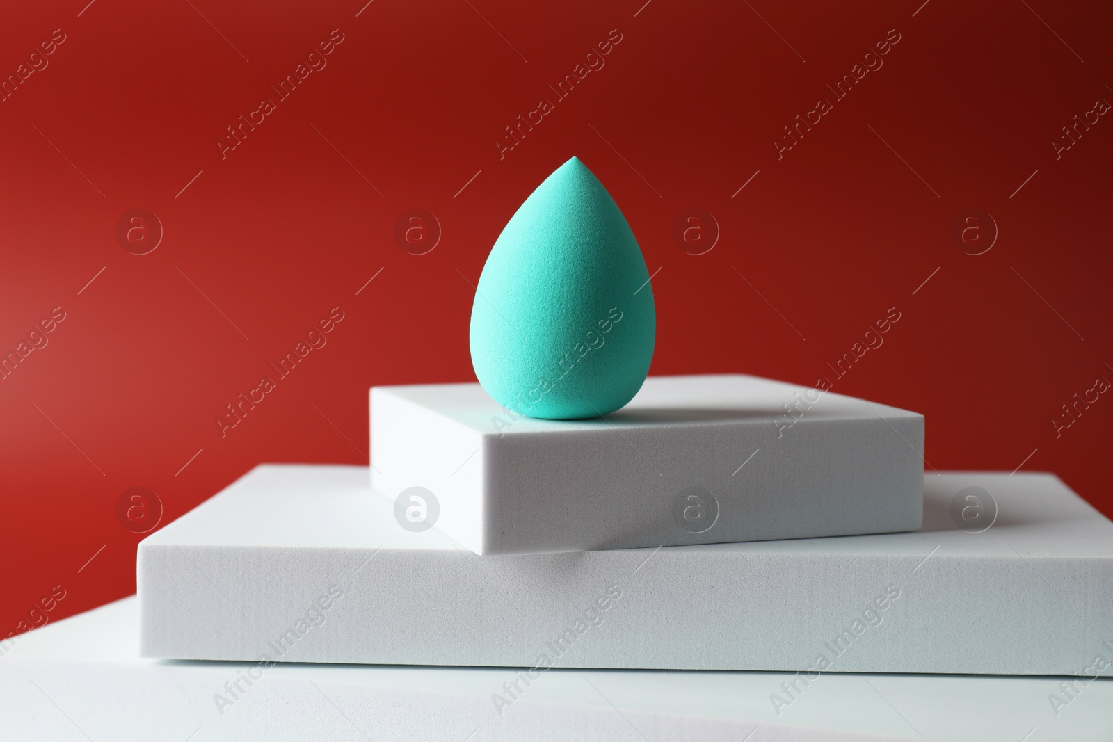 Photo of Stylish presentation of makeup sponge on red background