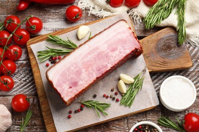 Photo of Piece of raw bacon with spices and cherry tomatoes on wooden table, flat lay