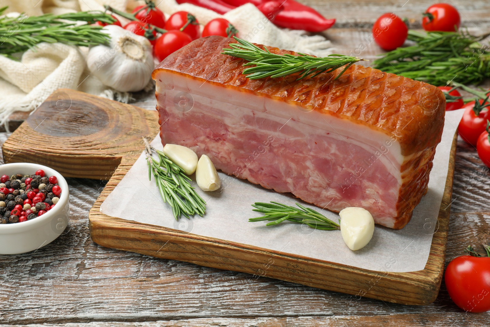 Photo of Piece of raw bacon with spices and cherry tomatoes on wooden table