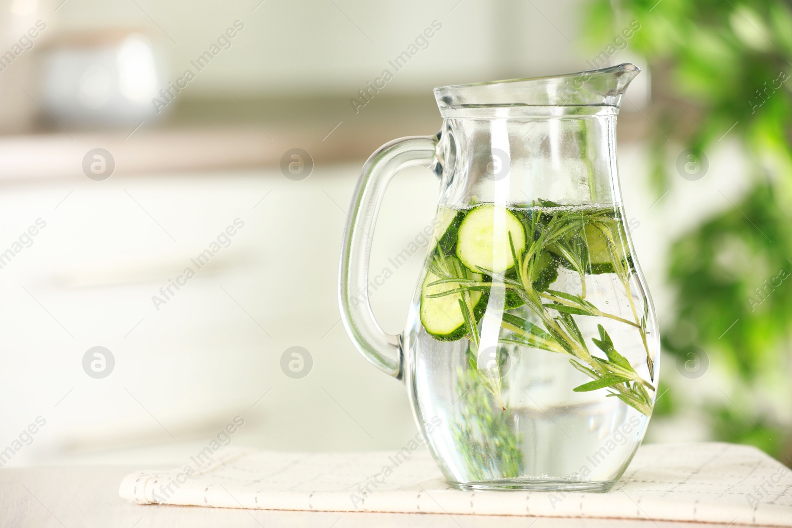 Photo of Refreshing cucumber water with rosemary in jug on white table, closeup. Space for text