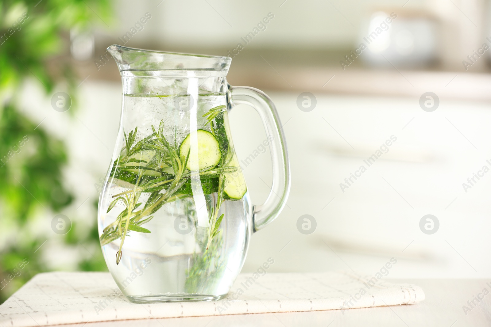 Photo of Refreshing cucumber water with rosemary in jug on white table, closeup. Space for text