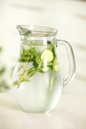 Photo of Refreshing cucumber water with rosemary in jug on white wooden table, closeup