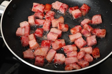 Pieces of bacon frying in pan, closeup