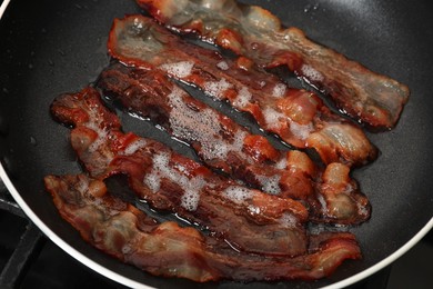 Slices of bacon frying in pan, closeup