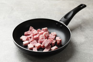 Pieces of fresh bacon in frying pan on grey textured table, closeup