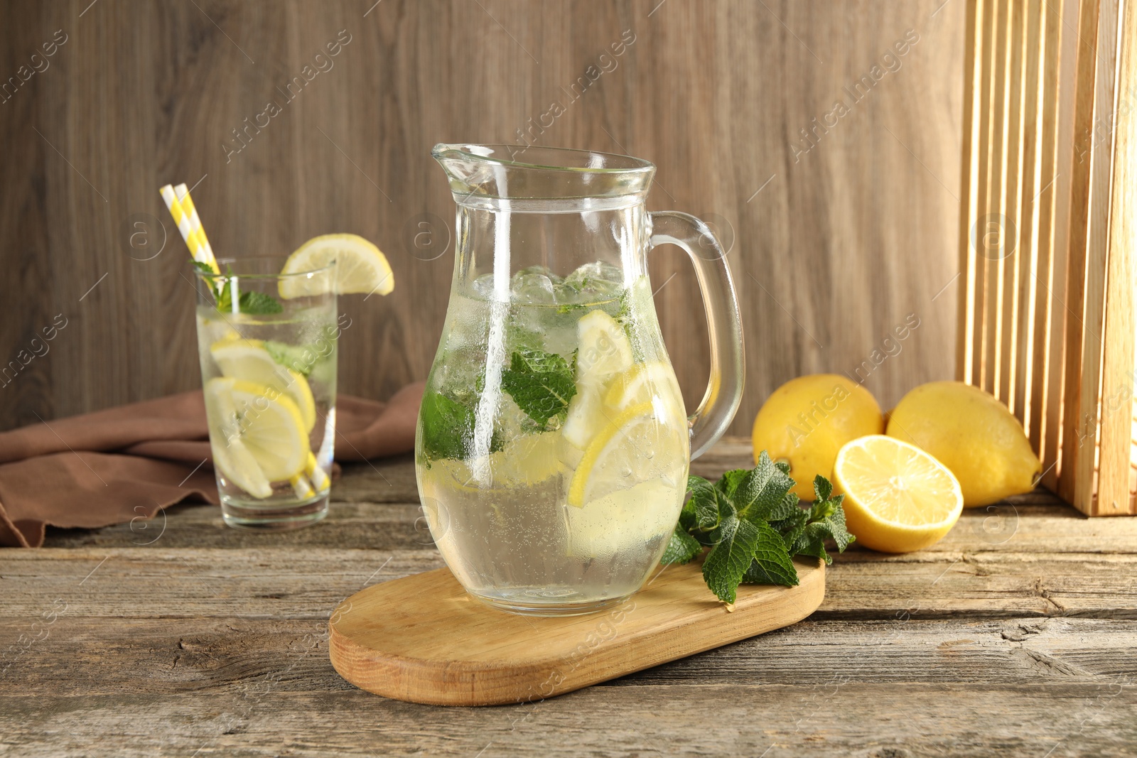 Photo of Refreshing lemonade with mint in jug and glass on wooden table