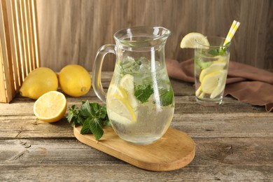 Photo of Refreshing lemonade with mint in jug and glass on wooden table